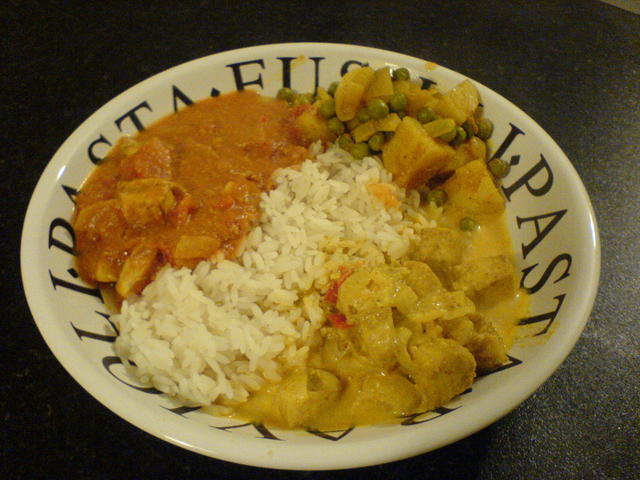 Butter Chicken served in a bowl with rice, tikka masala and potatoes and peas