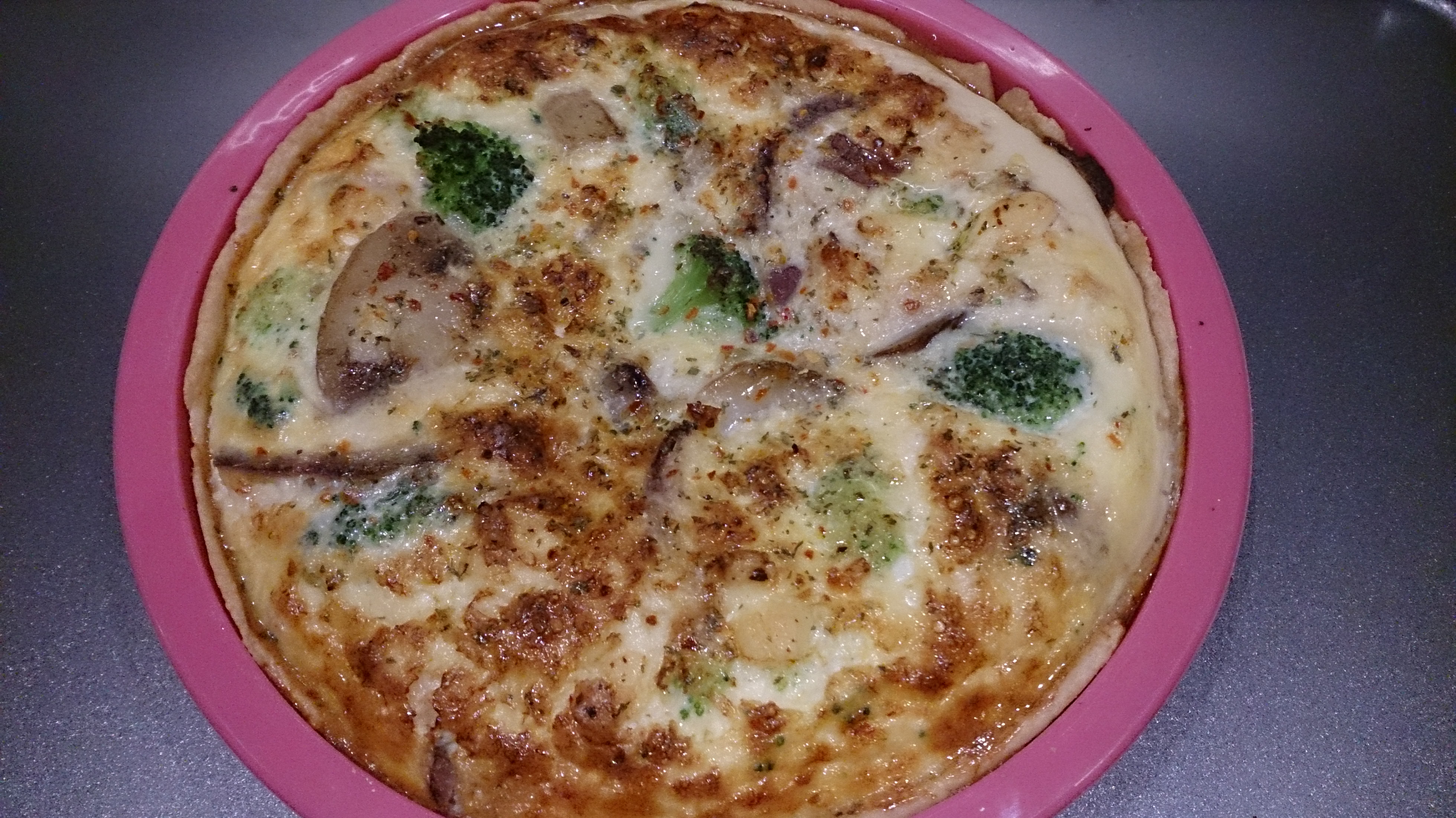 Cooked Quiche in a round pink silicone baking tin