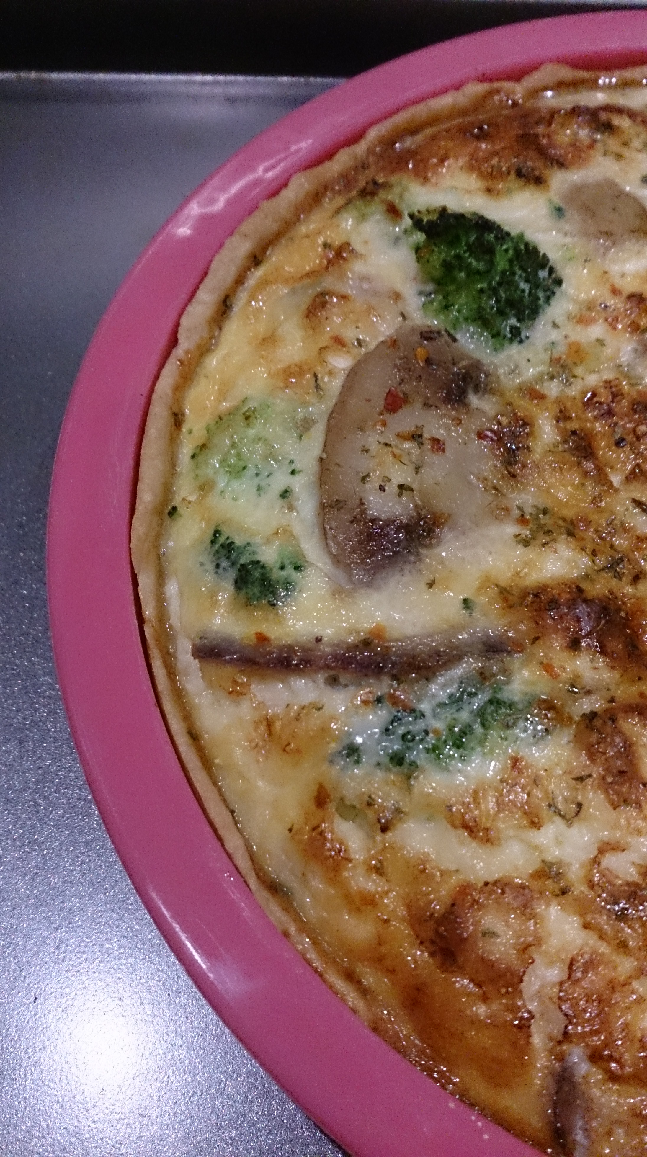 Closeup of Cooked Quiche in a round pink silicone baking tin