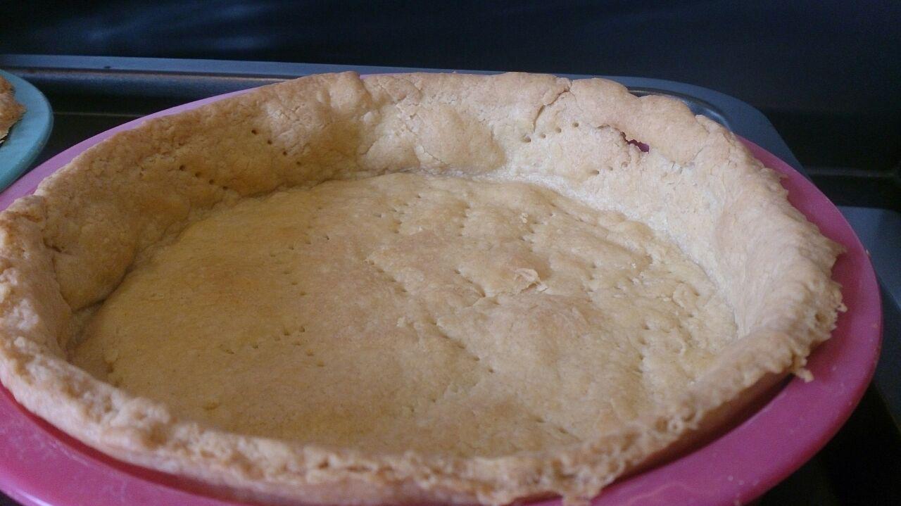 Empty quiche pastry in a round pink baking tin