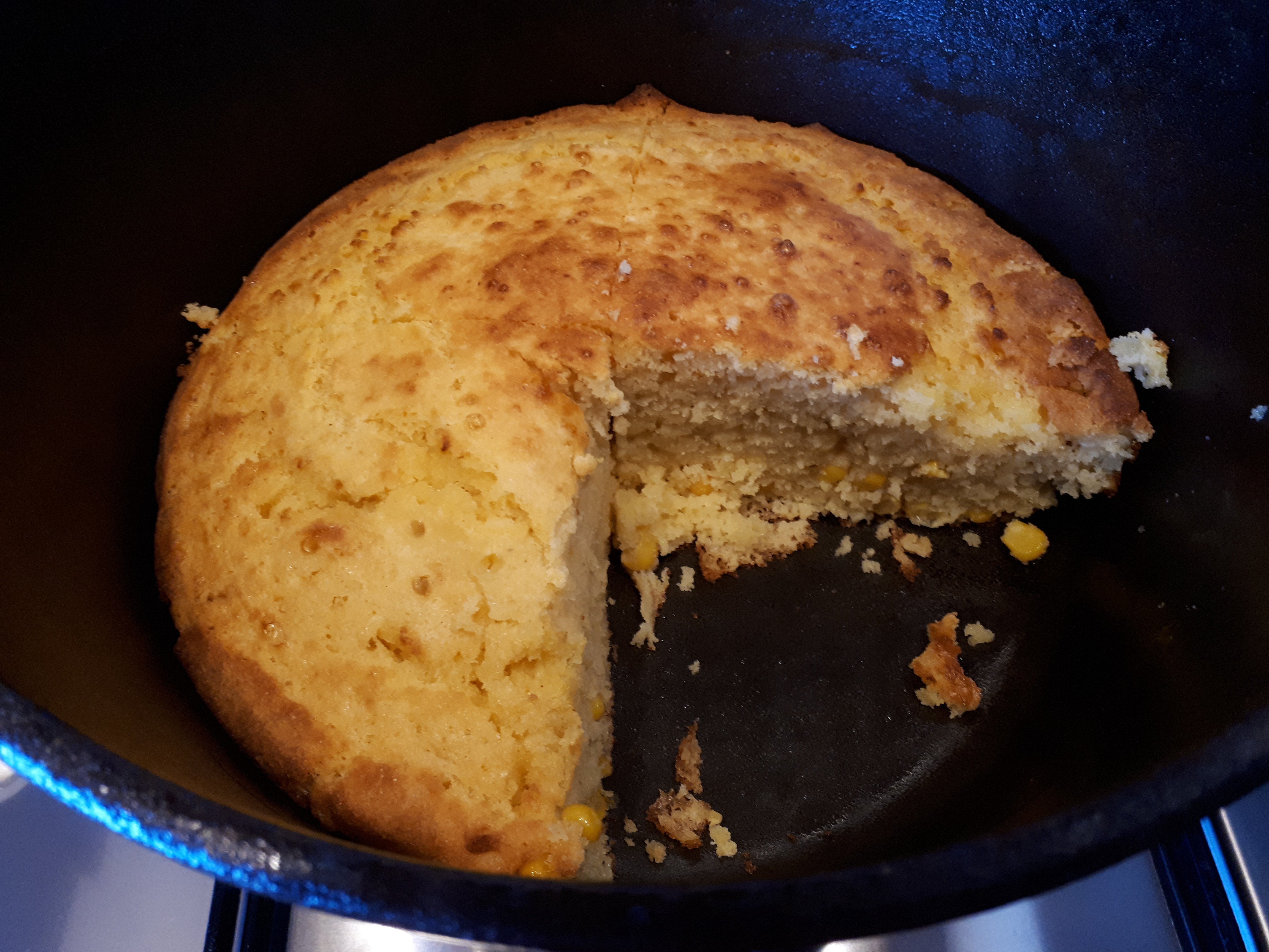 Sliced baked cornbread inside a cast iron Dutch oven