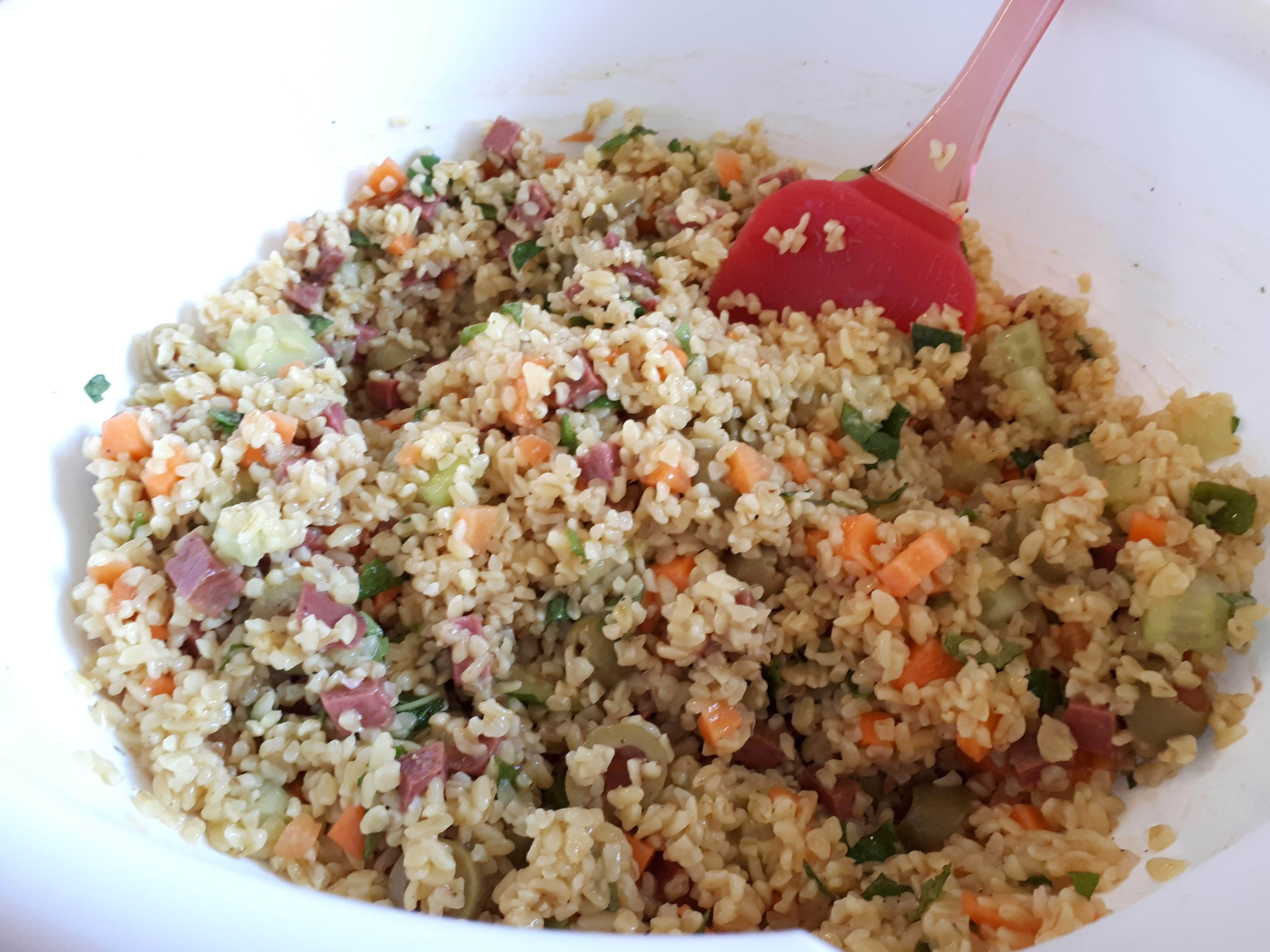 Bulgur Wheat Salad in a large white bowl with a red silicone spatula