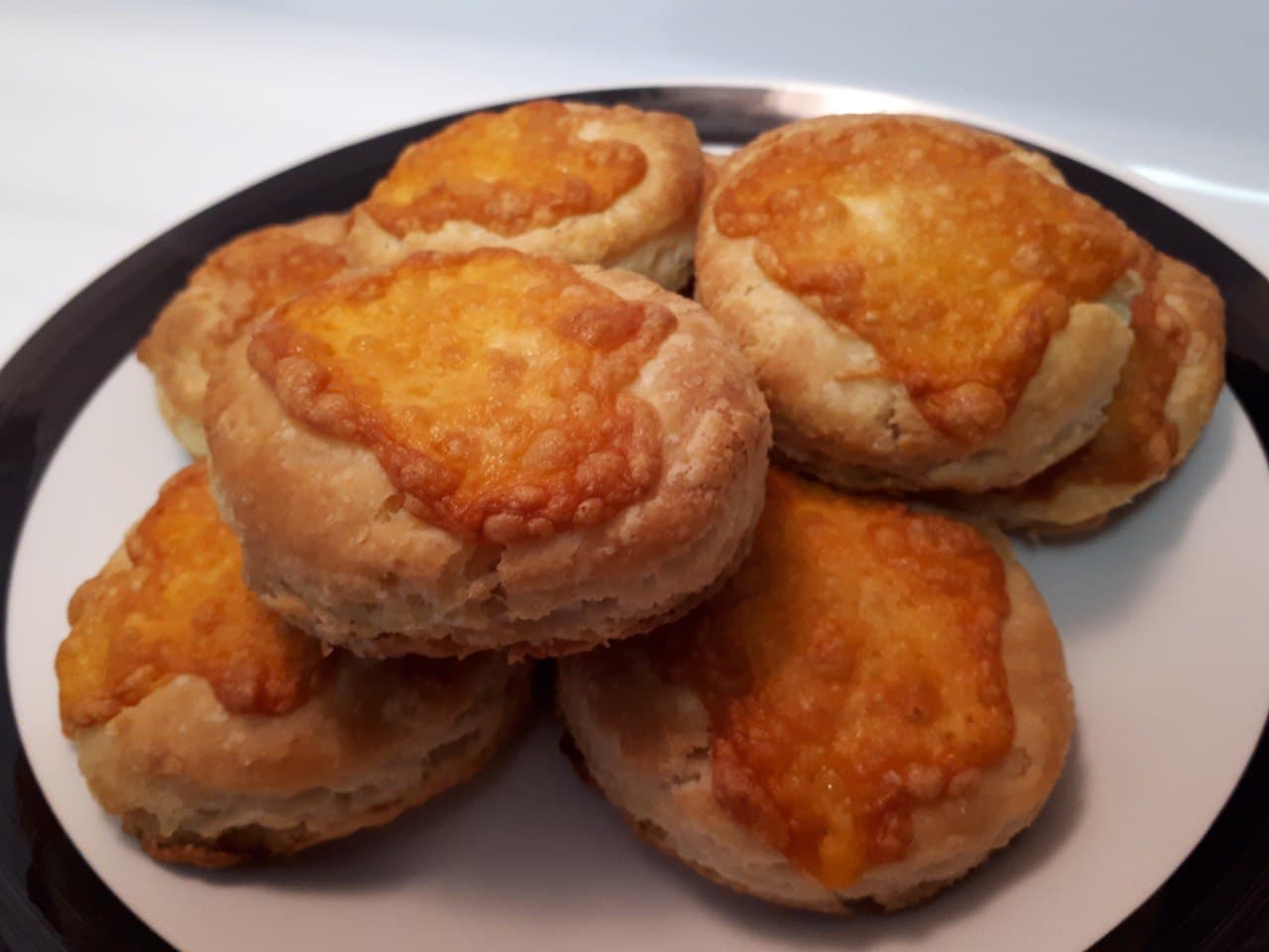 Sourdough Cheese Biscuits stacked on a white plate with black border