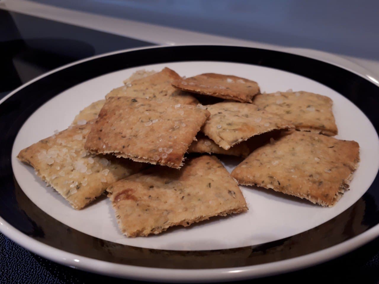 Sourdough Crackers stacked on a white plate with a black border