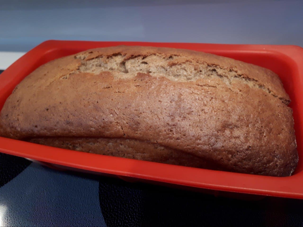 Baked banana bread in a red silicone loaf pan