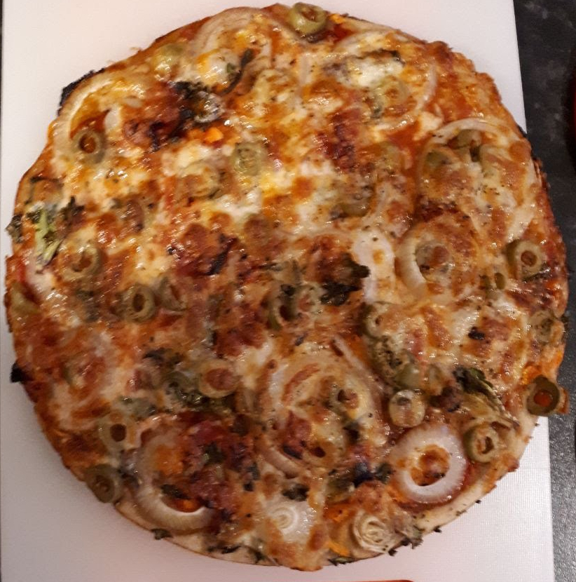 Cooked pizza in a cast iron pan with broccoli and cheese